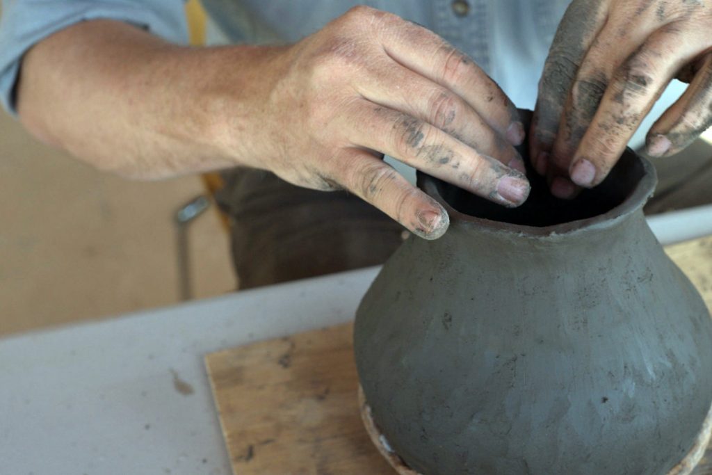 Potter hand building a jar